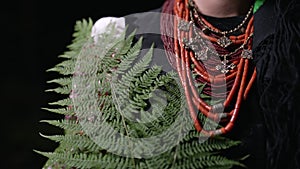 Authentic woman in traditional ukrainian necklace, costume with fern in forest at night. Lady in national dress -