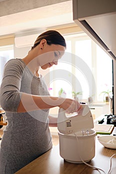 Authentic woman using a handheld mixer