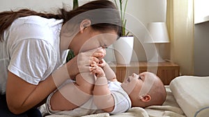 Authentic Young Caucasian Woman Holding Newborn Baby. Mom And Child On Bed. Close-up Portrait of Smiling Family With