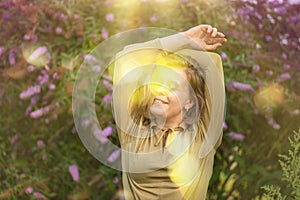 Authenticity emotions concept. Cheerful young woman smiling and enjoying nature near the buddleia flowers