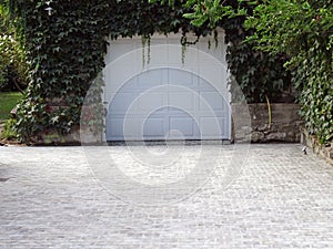 AUthenticity of a white garage door under dense green leaves of ivy