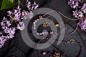 author collection jewelry with lilac gemstones, crystals and pearls demonstrated at black stones background. fashion and jewelry