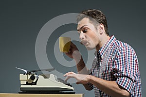 Author drinking coffee at typewriter