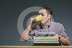 Author drinking coffee at typewriter