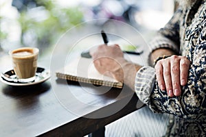 An author making notes in a coffee shop