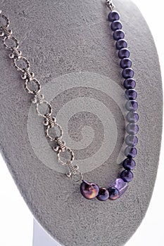 Author trend necklace with chain and purple reals  demonstrated  on maneken. fashion and jewelry concept