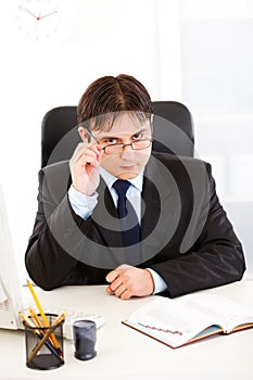 Authoritative businessman straightening eyeglasses