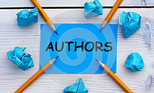 AUTHORS - word on blue paper on a light background with crumpled pieces of paper and pencils