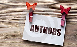 AUTHORS - word on a white sheet with beautiful clothespins on a wooden background