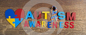 Autism awareness. Autism awareness ribbon, heart and word autism on wooden background background.