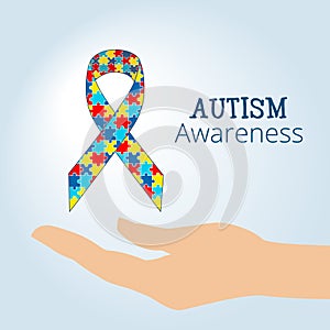 Autism awareness concept with hand holding ribbon of puzzle pieces