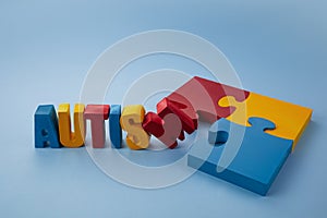 Autism awareness concept with puzzle and word autism on blue background.