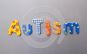 Autism word spelled out in bright colorful patterened letters on brushed metal background