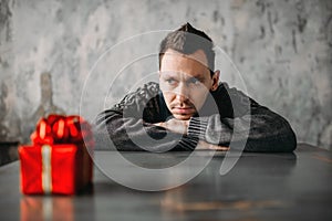 Autist man sitting against gift in wrapping paper