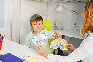 Autistic boy during ABA therapy with weather cards photo