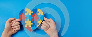 Autistic boy hands holding jigsaw puzzle heart shape. Autism spectrum disorder family support concept. World Autism