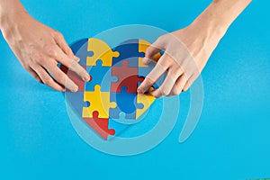 Autistic boy hands holding jigsaw puzzle heart shape. World Autism Awareness Day