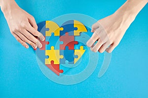 Autistic boy hands holding jigsaw puzzle heart shape. World Autism Awareness Day