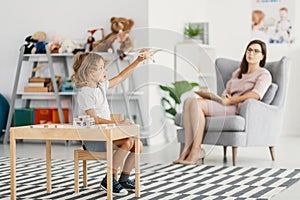 Autistic boy playing with toy during meeting with psychotherapist photo