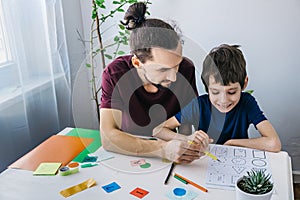 Autistic boy during therapy at home with his father with learning and having fun together. Autism awareness concept