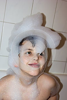 Autistic child in a cap of foam soap smiling creative son hat