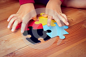 Autistic child`s hands playing jigsaw puzzle symbol of autism spectrum disorder.