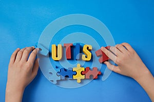 Autistic kid hands holding puzzle jigsaw and word autism, mental health concept. Autism spectrum, disorder. World autism