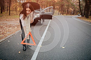 Auto assistance and insurance, troubles while traveling concept. Broken car and auto triangle on road, woman waiting for