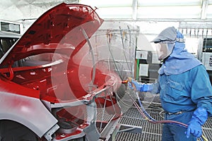 An auto body is spray painted by and human operator in the paint shop. photo