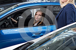 Auto business, car sale, consumerism and people concept - happy woman with car dealer in auto show or salon
