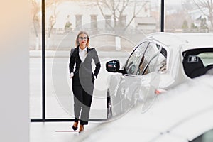 Auto business, car sale, consumerism and people concept - happy woman taking car key from dealer in auto show or salon
