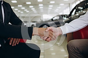 auto business, car sale, deal, gesture and people concept - close up of dealer giving key to new owner and shaking hands