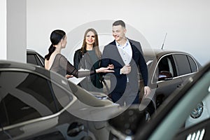 Auto business, car sales - a happy couple with a car dealer in a car dealership or salon.