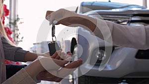 Auto business, family hands of owners car take keys on background of automobile close-up in sales center