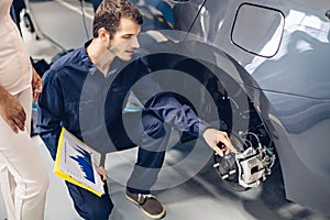 Auto car repair service center. A female customer and mechanic checking car breaks
