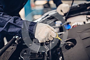 Auto car repair service center. Mechanic checking engine oil level