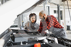 Auto car repair service center. Mechanic examining car engine. Female Mechanic working in her workshop. Auto Service Business