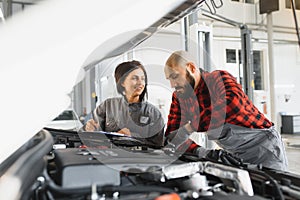 Auto car repair service center. Mechanic examining car engine. Female Mechanic working in her workshop. Auto Service Business