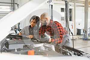 Auto car repair service center. Mechanic examining car engine. Female Mechanic working in her workshop. Auto Service Business