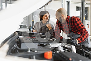 Auto car repair service center. Mechanic examining car engine. Female Mechanic working in her workshop. Auto Service Business