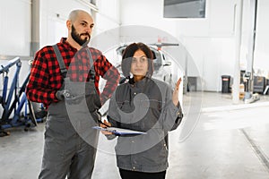 Auto car repair service center. Mechanic examining car engine. Female Mechanic working in her workshop. Auto Service Business