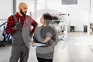 Auto car repair service center. Mechanic examining car engine. Female Mechanic working in her workshop. Auto Service Business