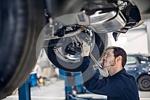 Auto car repair service center. Mechanic examining car suspension