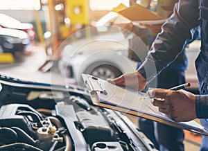 Auto check, car service shop concept. Automobile repairman writing job checklist on clipboard, mechanic checking engine