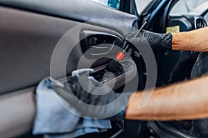 Auto detailing, worker cleans door trim with brush