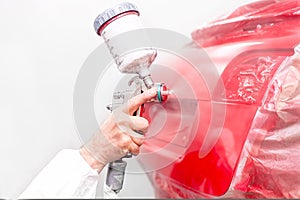 Auto engineer painting a red paint on modern car in special booth