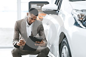 Auto Insurance Agent Sitting Taking Notes Working In Dealership Center
