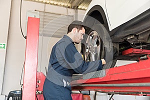 Auto Mechanic Adjusting Car Tire In Repair Shop