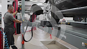 Auto mechanic aligns car wheels with high-precision equipment in garage. Expert conducts vehicle maintenance, ensures