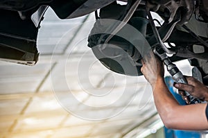 Auto mechanic asian checking bush-bolt under double wishbone suspension by hand with tools car lift